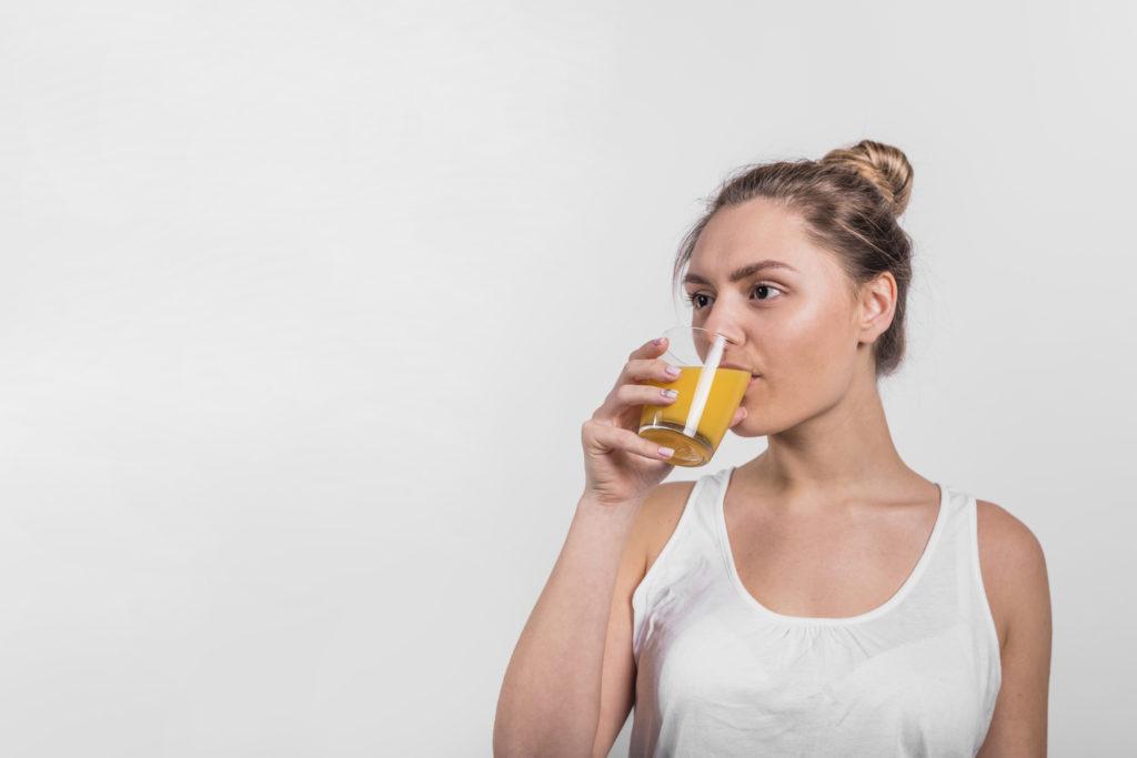 MUJER JOVEN BEBIENDO JUGO NARANJA LICUADO AGUA TOMANDO SUMPLEMENTO VITAMINICO